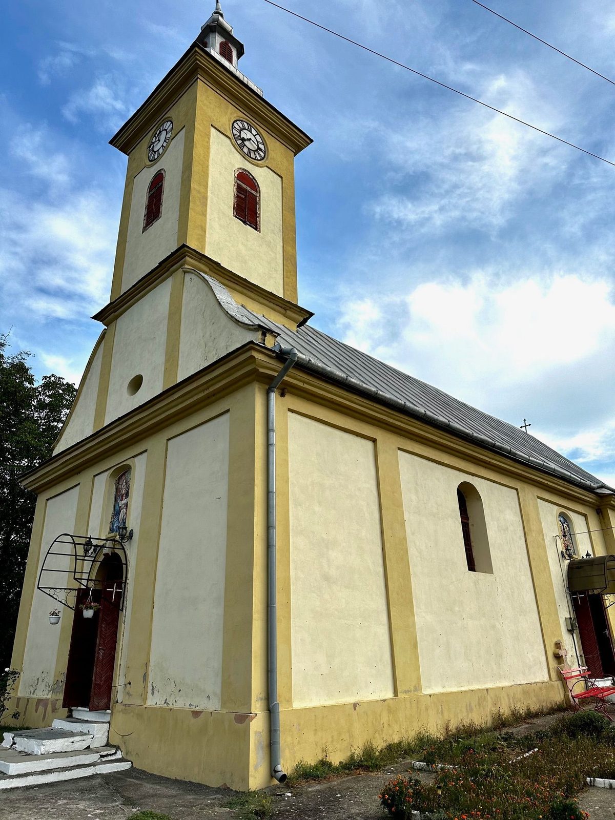 Fațada bisericii ortodoxe din Sasca Montană, cu turnul-clopotniță și ceasul de sub cruce