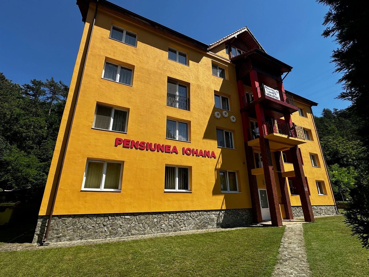Fațada galbenă a Pensiunii Iohana într-o dimineață de vară