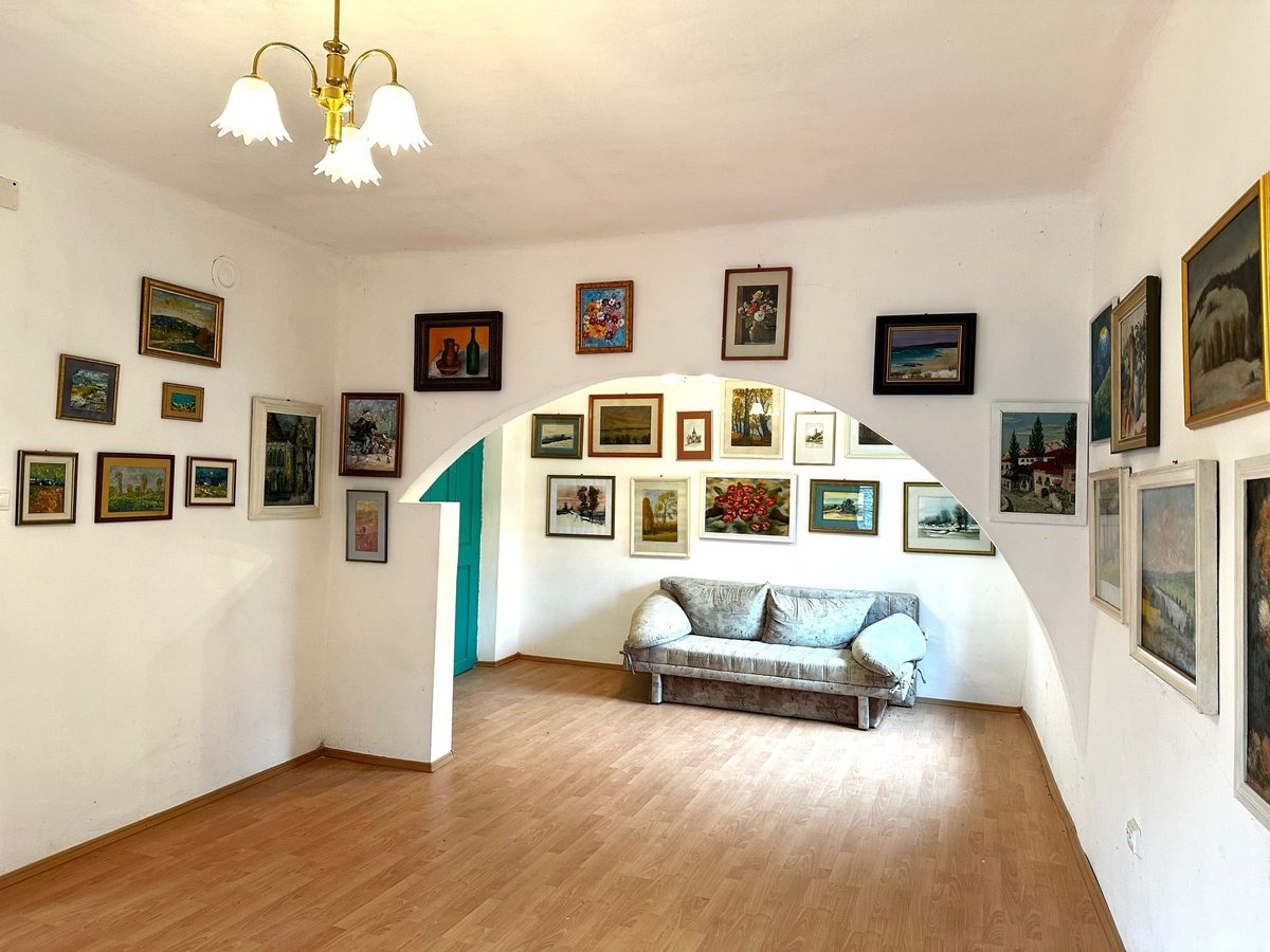 Arcul de zidărie al galeriei, cu tablouri de jur împrejur și o canapea așezată sub el