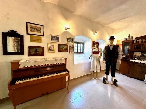Sala boltită a Muzeului Germanității, cu un pian vertical acoperit de o față de masă dantelată și două manechine în port șvăbesc lângă fereastră