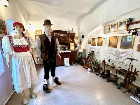 Manechine în port șvăbesc de sărbătoare — ea cu bonetă roșie și șorț alb, el cu pălărie și vestă de catifea — în fața unui bufet de nuc