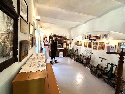 Sala lungă a Muzeului Germanității, cu gravuri înrămate pe amândoi pereții și unelte de gospodărie înșirate pe podea