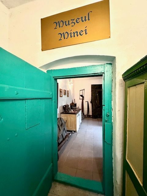 Ușa verde a Muzeului Minei, cu firma aurie scrisă cu litere gotice deasupra pragului