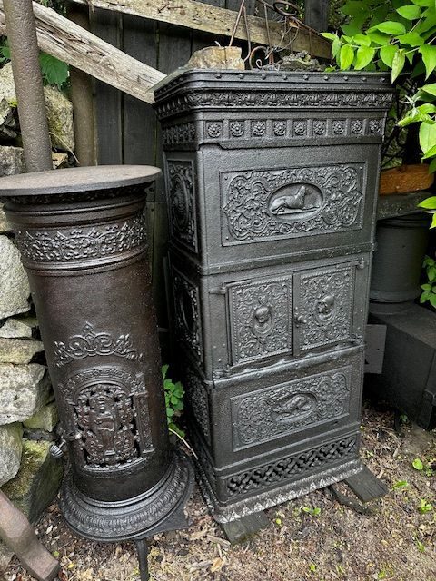 Două sobe de fontă turnate cu ornamente, scoase în curtea muzeului lângă zidul de piatră