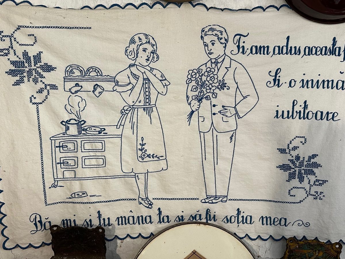 Ștergar brodat cu albastru, cu o fată la plită și un flăcău cu flori, și versul cusut dedesubt: „Dă-mi și tu mâna ta și să fii soția mea”