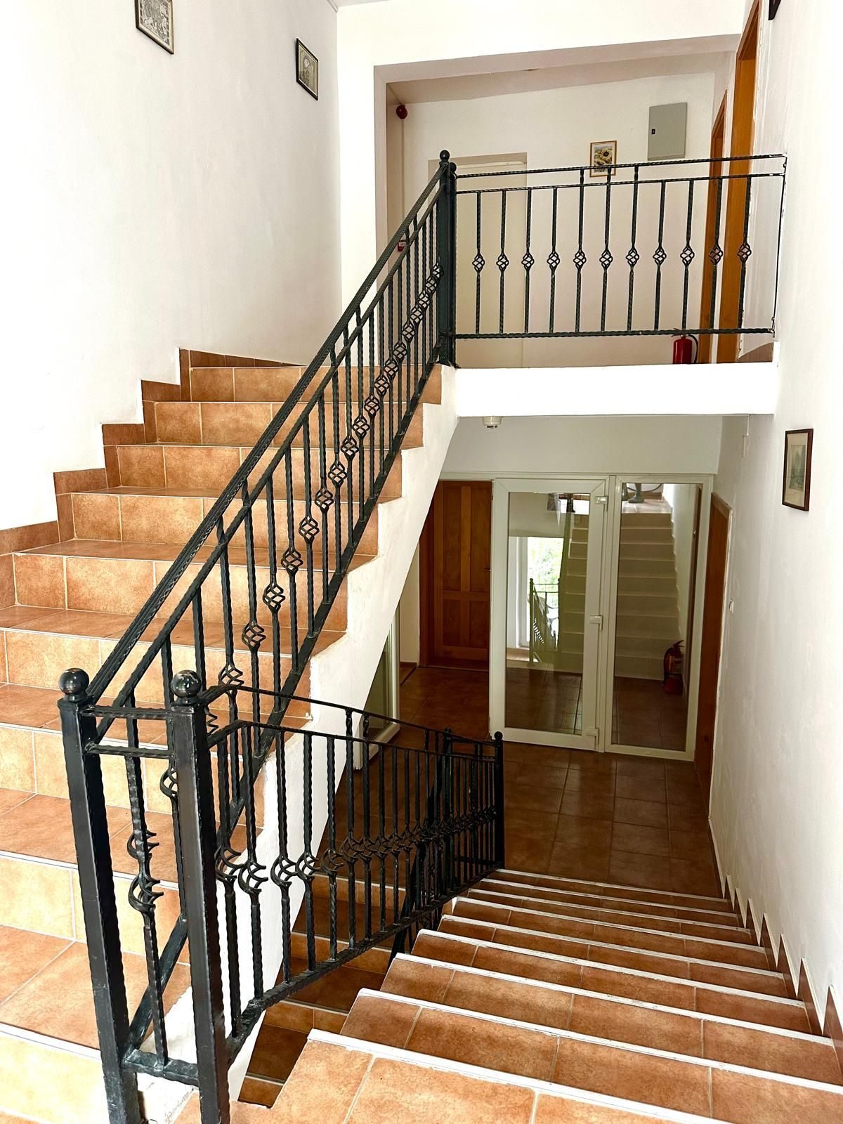 Scara centrală a pensiunii, cu trepte de gresie și balustradă de fier forjat, văzută de la etaj